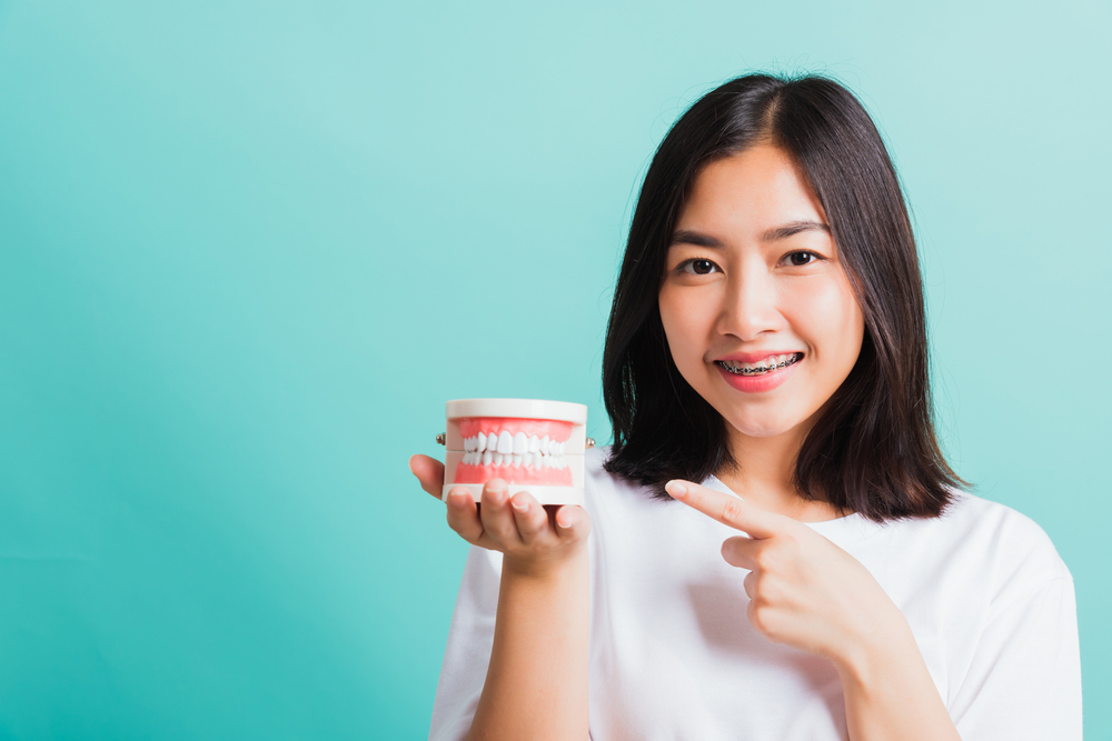Woman holding a fake teeth - Dentures in Olympia WA